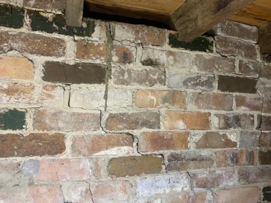 Brick wall with horizontal and vertical cracks indicating subsidence and foundation repair needs.